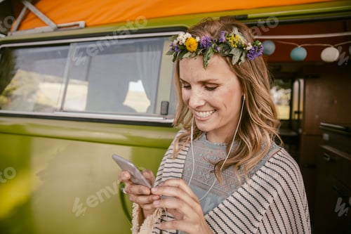 Preview: Hippie woman listening to music from her smartphone in front of van