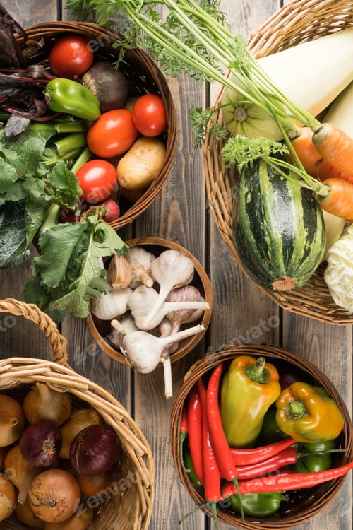 Preview: Wicker baskets with different fresh garden vegetables on wooden table, top view. Bowls full harvest
