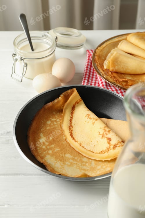 Preview: Concept of tasty breakfast with thin pancakes on white wooden table