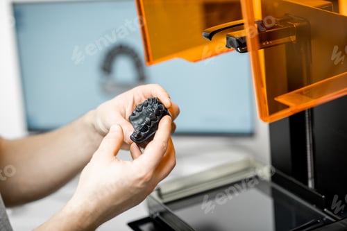 Preview: Dental technician removing jaw model from a 3d printer