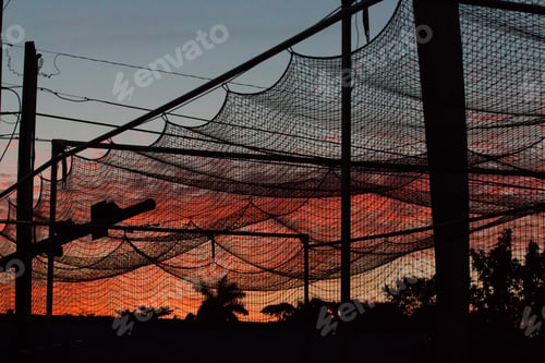 Preview: Sunset at the baseball field with a silhouette of the batting cage netting