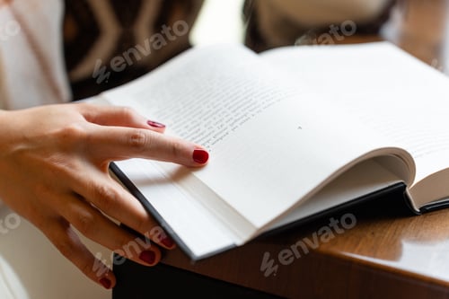 Preview: Close-up of a woman's hand turning the page of a book she is reading