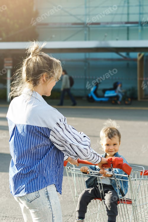 Preview: Young mother and her cute little son are having fun with shopping cart
