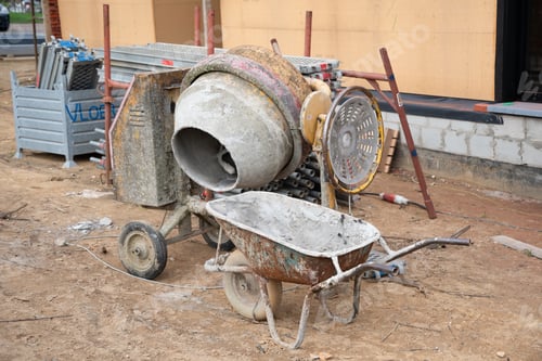 Preview: dirty concrete mixer near the construction of a house on the ground building
