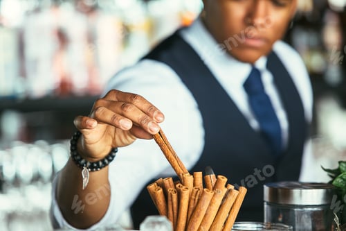 Preview: Detail of the hand of a bartender takes cinnamon stick