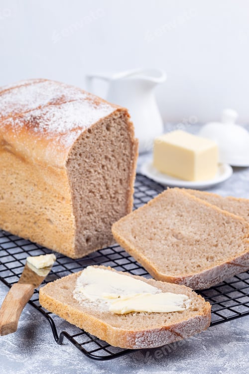 Preview: Slices of homemade no knead sandwich bread with butter, on cooling rack, vertical