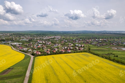 Preview: Aerial view of ground road with moving cars in green fields with blooming rapeseed plants