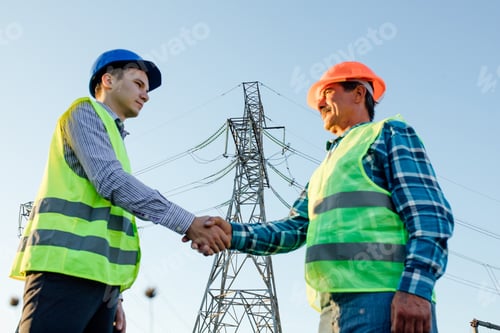 Preview: Engineers shaking hands against high voltage tower