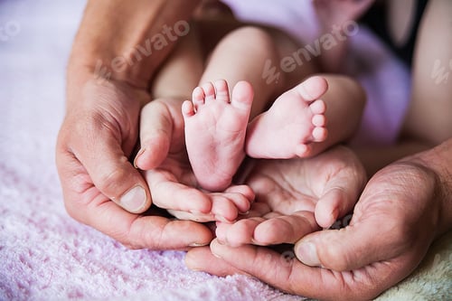Preview: Baby feet in father hands on purple