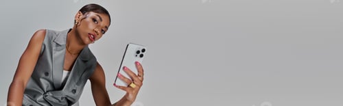 Preview: Stylish young woman captures her essence in a chic studio setting with her smartphone