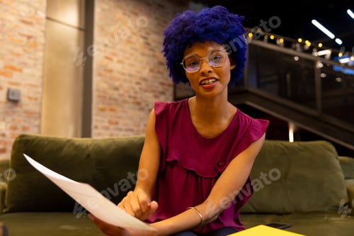 Preview: Happy biracial casual businesswoman with blue afro making video call in office