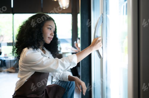 Preview: The owner of a coffee shop looks inside the refrigerator to retrieve chilled food