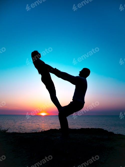 Preview: Beautiful silhouettes of yoga people on sunset or sunrise background