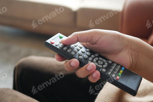 Preview: close up of women hand holding tv remote.