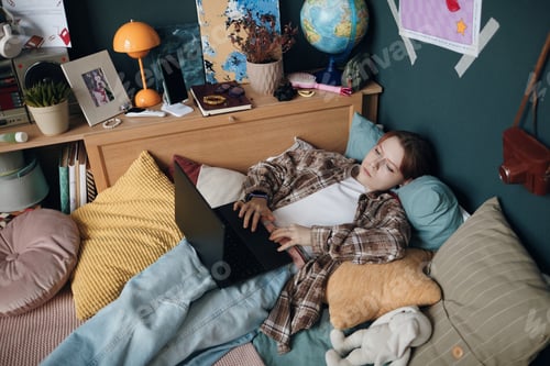Preview: Caucasian Teenager Girl Using Laptop While Relaxing on Bed in Cozy Room