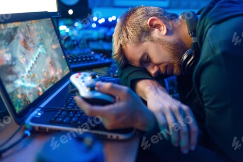 Preview: Male gamer sleeping at his laptop after challenge