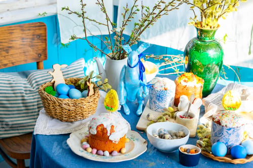 Preview: table set for Easter on veranda on sunny spring day decorated with flowers and Easter decor, eggs, c