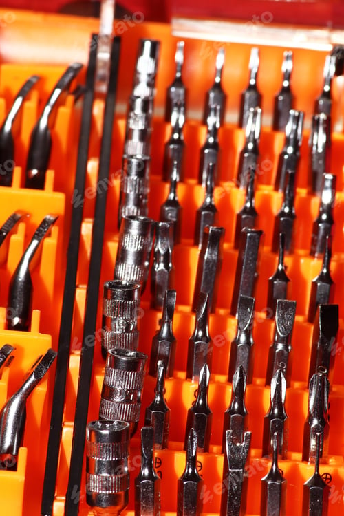 Preview: Vertical shot of electronics screwdriver set aligned on an orange surface