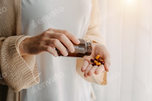 Preview: Woman with glass of water and three pills on hand going to take medicaments prescribed
