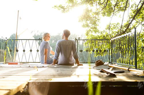 Preview: Young couple sitting on a jetty next to sailing boat