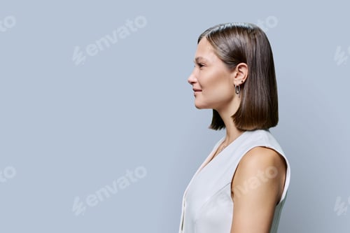Preview: Profile view of young fashionable woman with on gray background