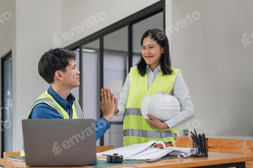 Preview: Construction engineer with blueprint making high five while standing on construction site. Home