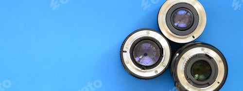 Preview: Several photographic lenses lie on a bright blue background. Space for text