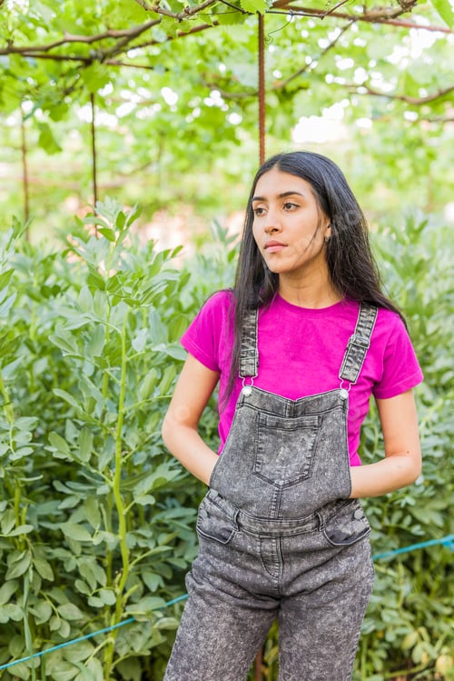 Preview: Venezuelan Latin young woman gardening and harvesting in urban garden portrait