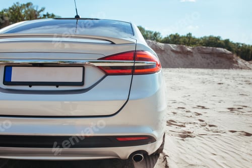 Preview: taillight and bumper of a gray car standing on the sand