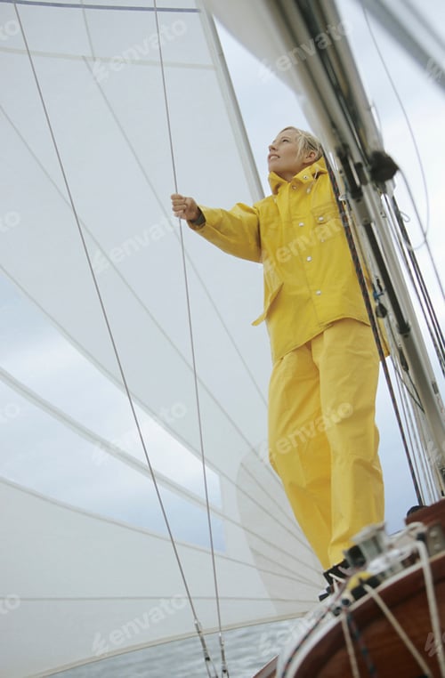 Preview: Woman adjusting sail on boat