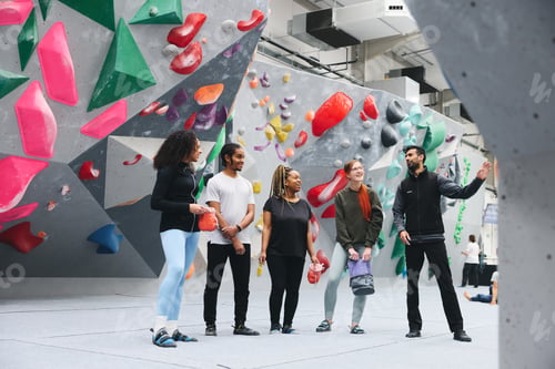 Preview: Group Of Friends Being Safety Given Briefing By Male Coach At Indoor Wall Climbing Centre