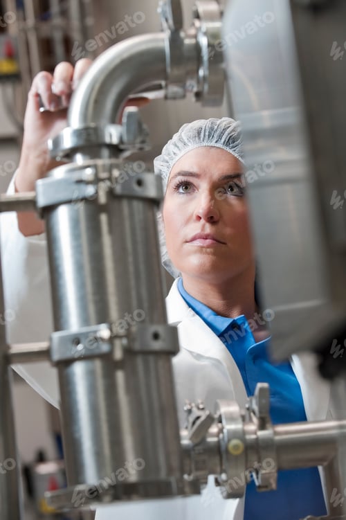 Preview: Technician checking large stainless steel processing tanks in a bottling plant.