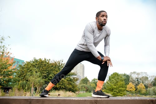 Preview: Young black man stretching legs before running in city park