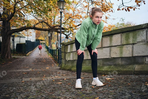 Preview: Tired sporty girl resting after run in beautiful autumn park