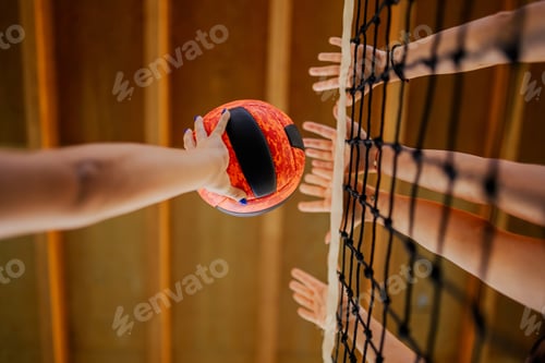 Preview: Close up of volleyball players' hands blocking a ball over net.