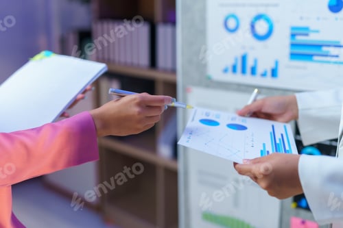 Preview: Businesswomen analyzing financial data documents during meeting