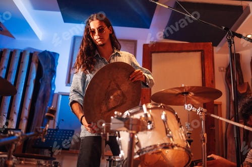 Preview: Young drummer setting up a ride cymbal in a music studio.