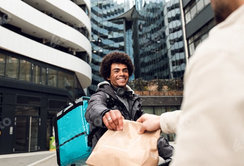 Preview: Male courier with bicycle delivering fast food to the customer in city.