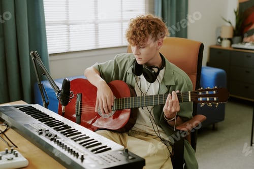Preview: Caucasian Teenager Boy Recording Music Playing Acoustic Guitar at Home Studio