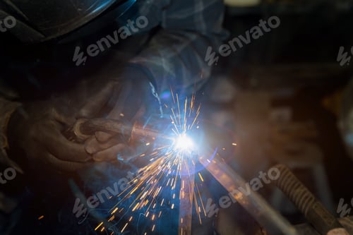 Preview: Worker welding a metal with sparkles on it, using a semi automatic welding machine shielded by an