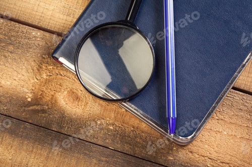 Preview: Magnifying glass and book o the wooden background