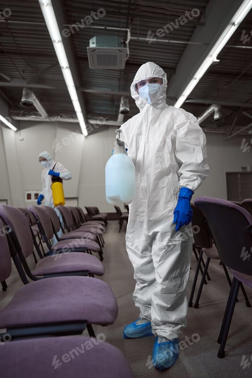 Preview: Cleaner wearing personal protective gear during disinfection of furniture