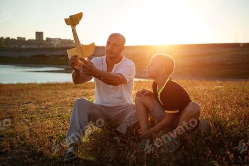 Preview: dad and son play the plane at sunset