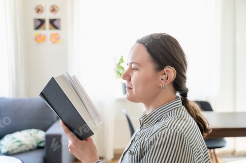Preview: Portrait of woman with hearing aid reading book