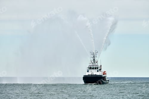 Preview: Fireboat ship sails on open sea directing jets of water to sides demonstrating bravery water salute