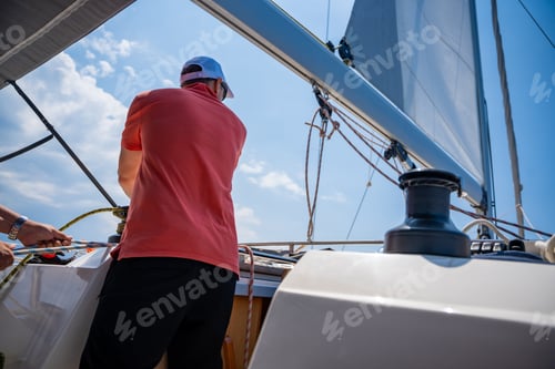 Preview: Mans pulling winch rope on sailing boat