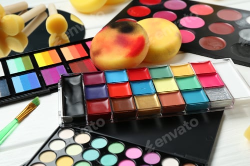 Preview: Face paints, tools and makeup products on white background, closeup