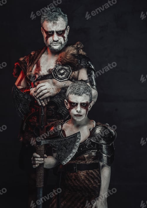 Preview: Boy warrior and his father armed with axes in dark background