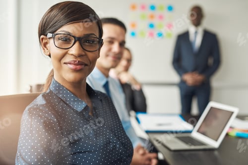 Preview: Cheerful female seated with colleagues in meeting