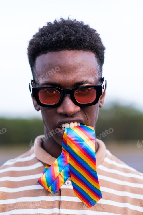 Preview: Portrait of young guy biting a tie with LGBTI rainbow colors